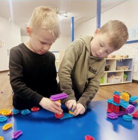 Two children playing with colorful building blocks at a table