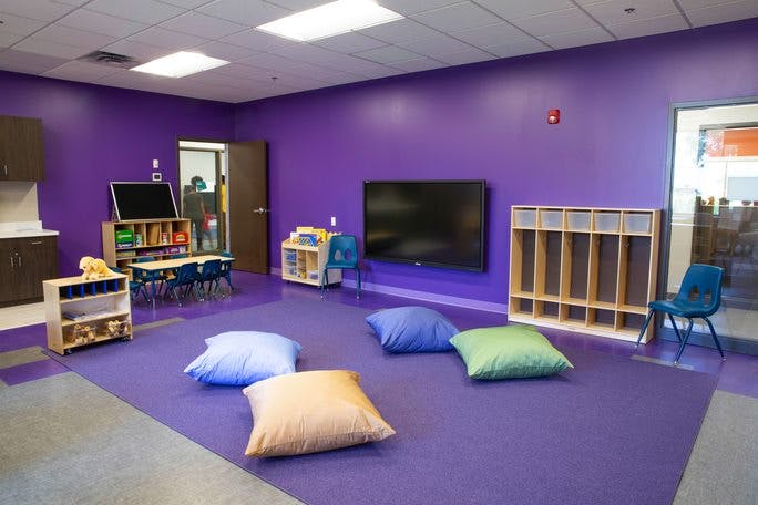 Classroom with purple walls and floor, floor cushions, and small tables