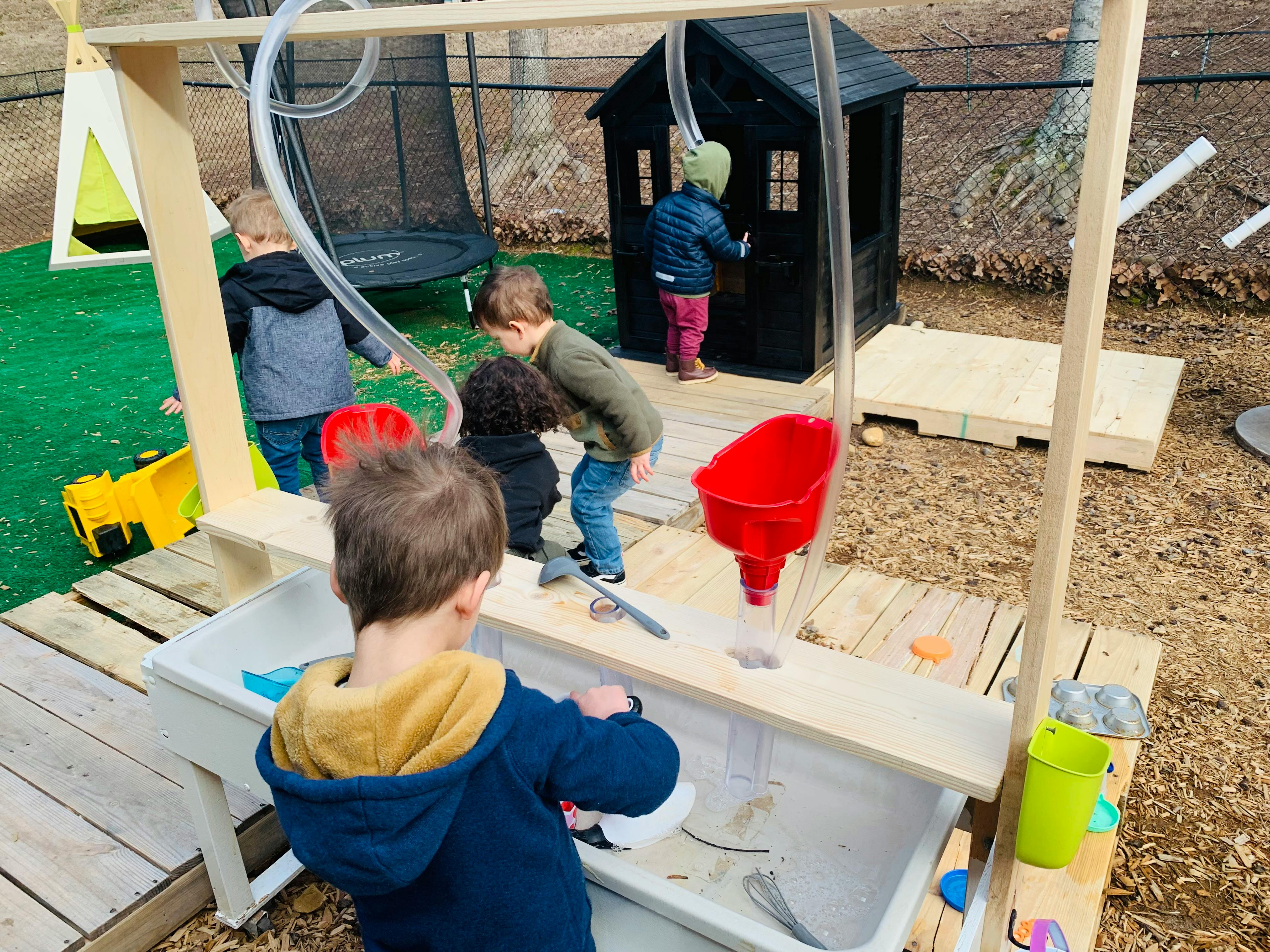 Children playing at a water table with funnels and tubes