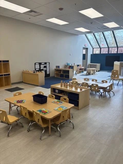Classroom with small tables and chairs, shelves, and large windows