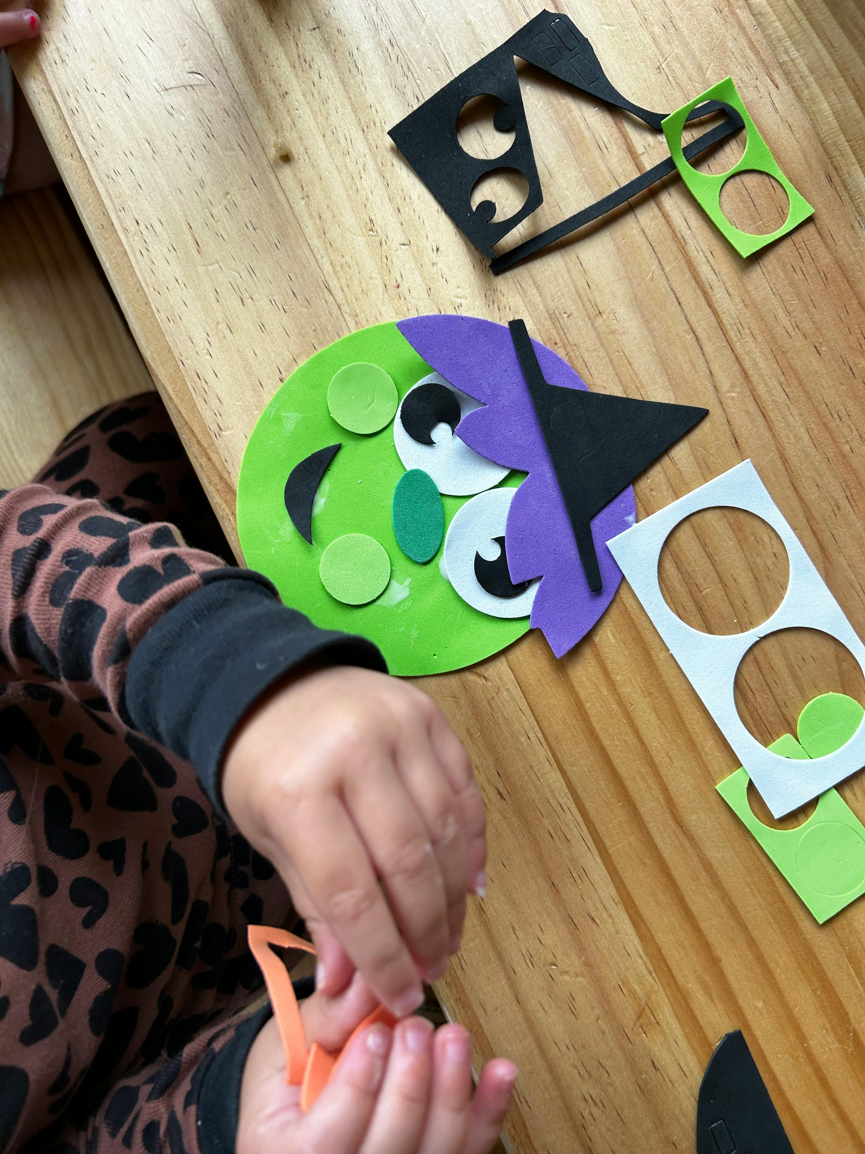 Child's hands working on a craft project with foam cutouts