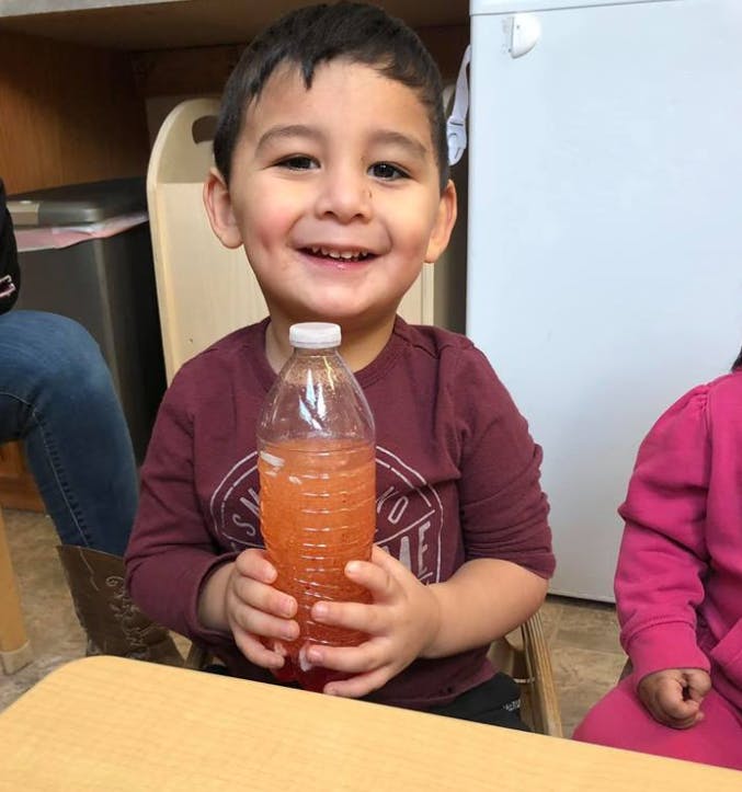 Child holding a bottle of liquid