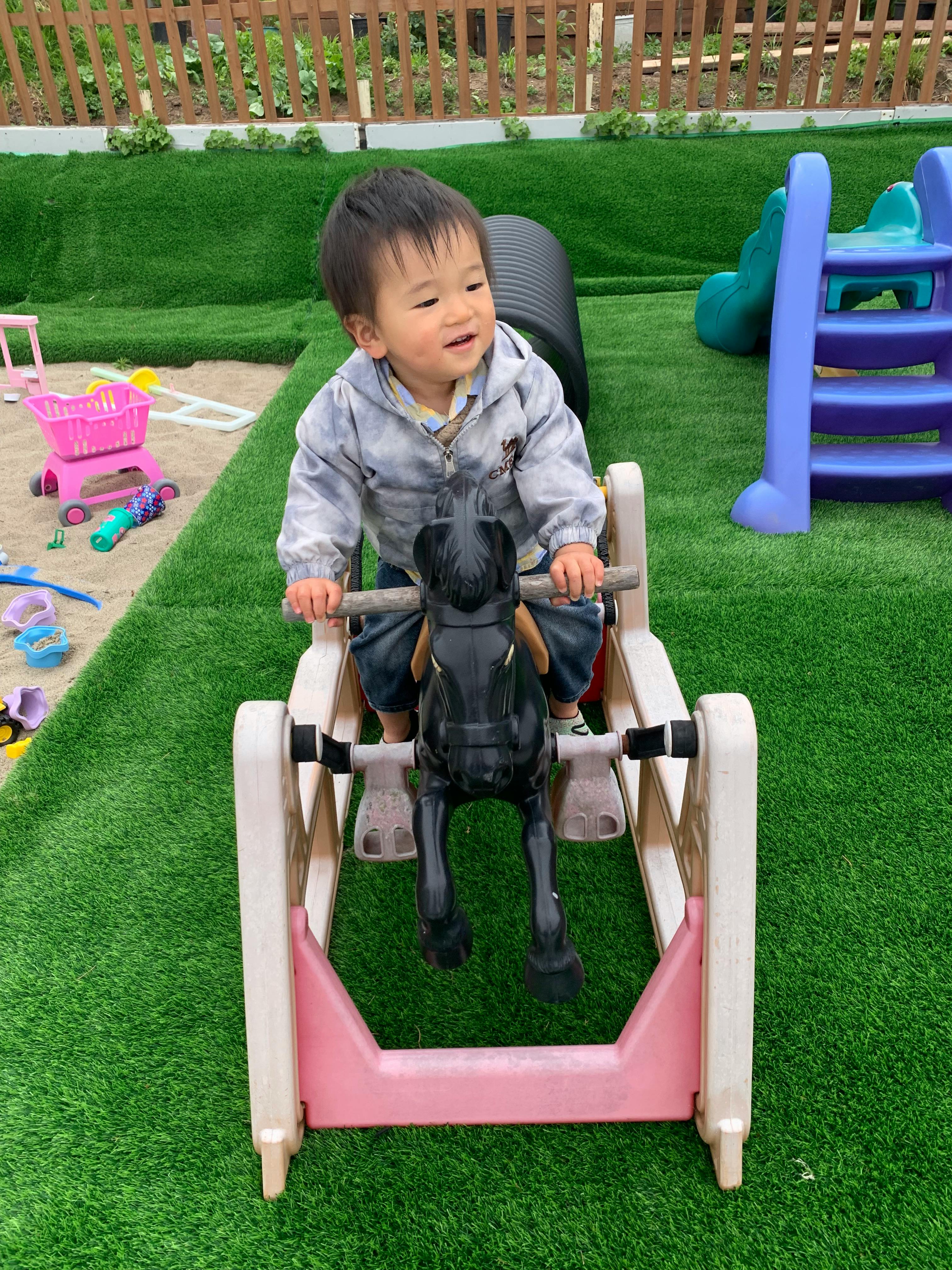Child riding a toy rocking horse on a playground