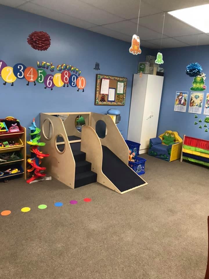 Indoor play area with a wooden climbing structure, slide, and colorful decorations