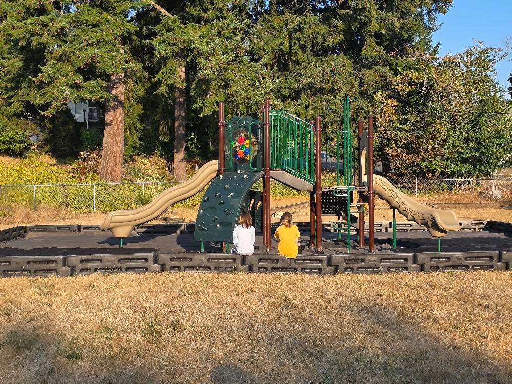 two children sitting on playground equipment