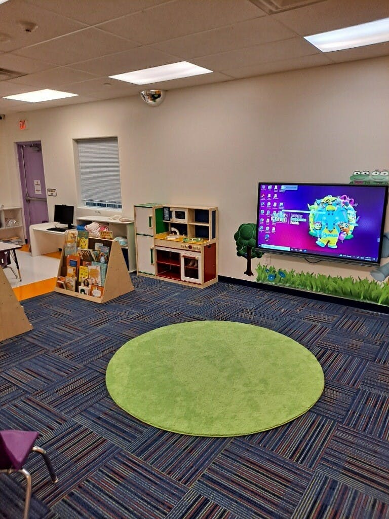 Children's play area with a large screen, toy kitchen, and book display
