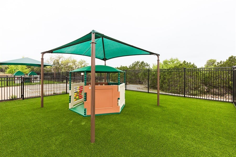 Playground with a green shade structure over a small playhouse