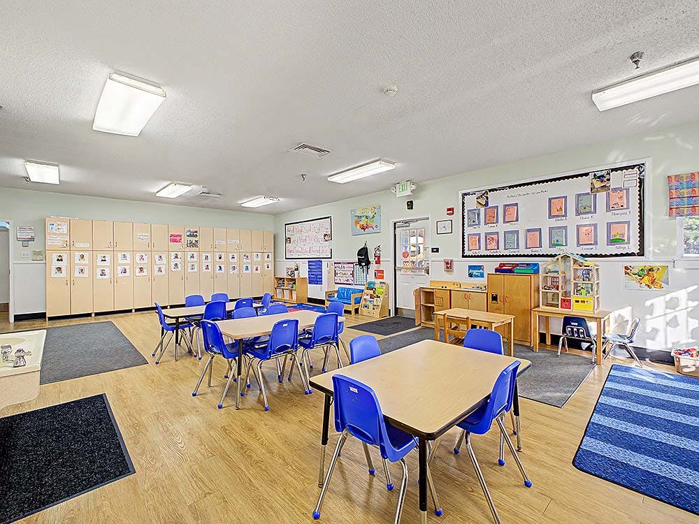 Empty classroom with small blue chairs, tables, and cubbies