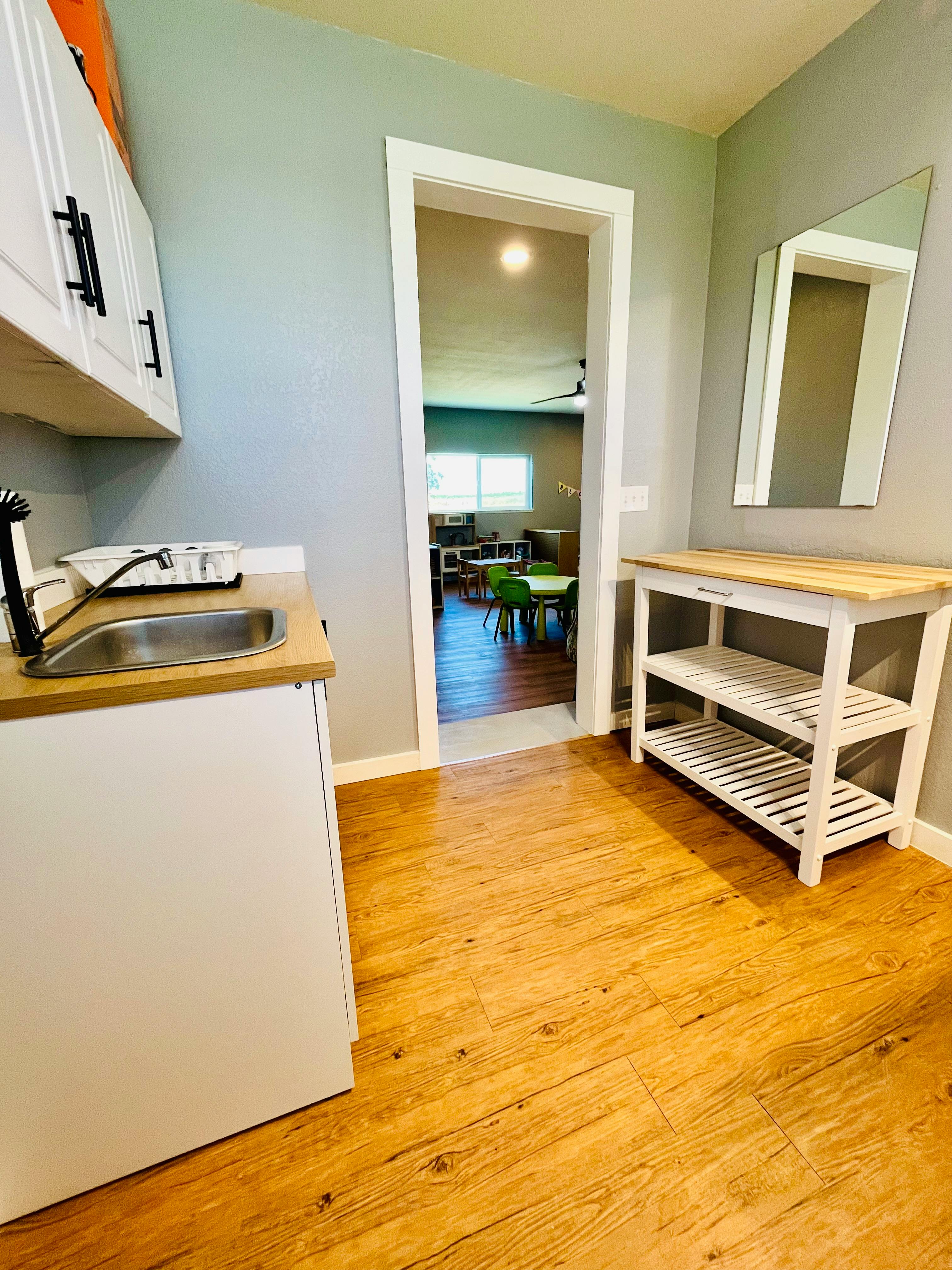 Kitchenette area with sink and cabinets, doorway leading to another room