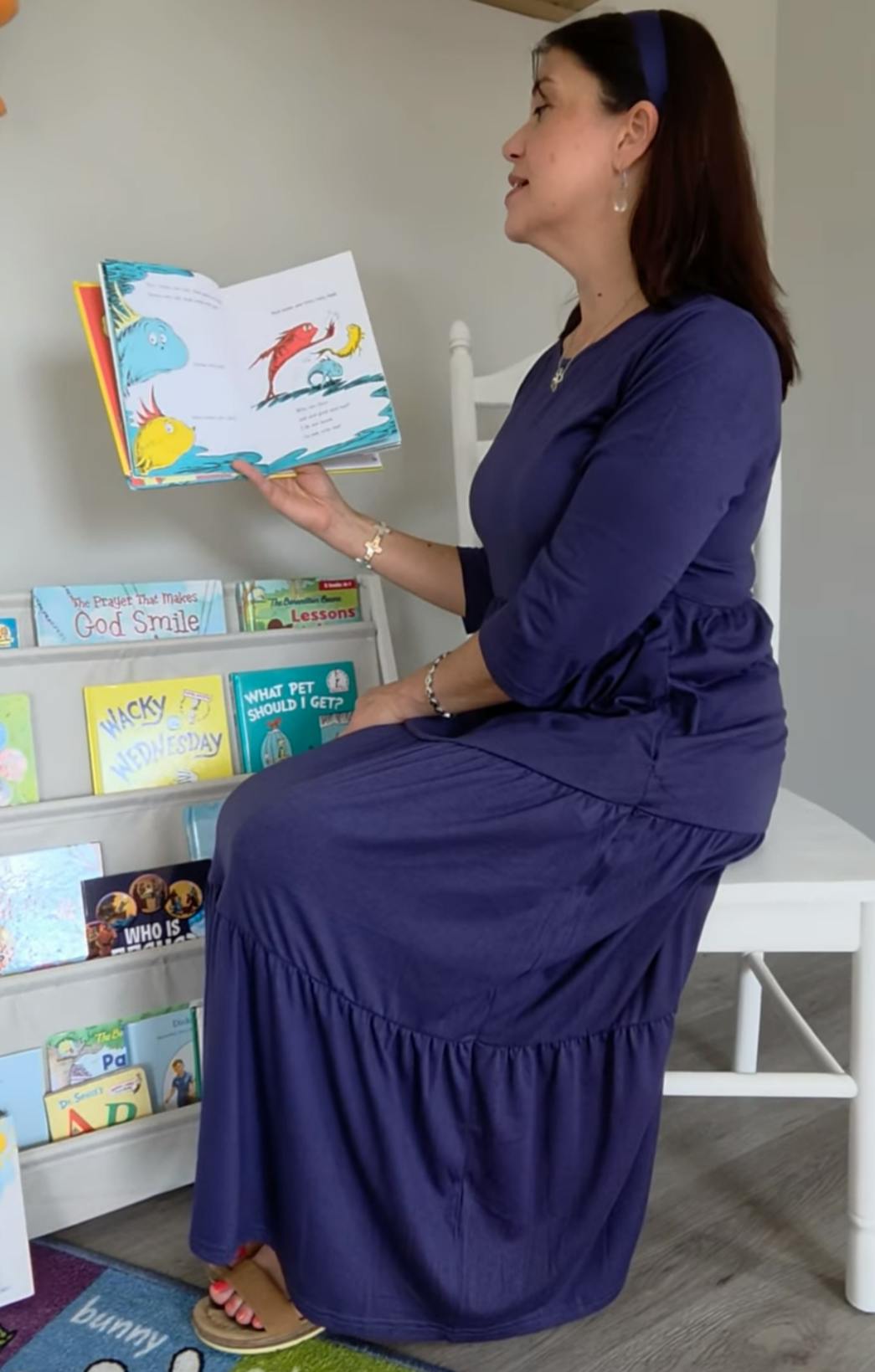 A person sitting on a white chair reading an open picture book