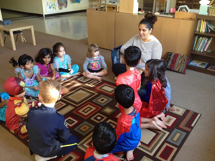 Adult and children sitting on a rug in a classroom