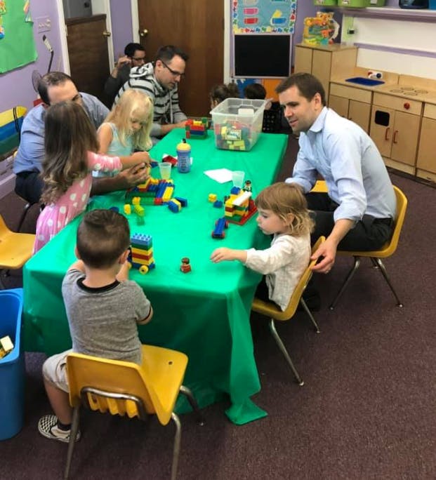 Adults and children playing with building blocks at a table