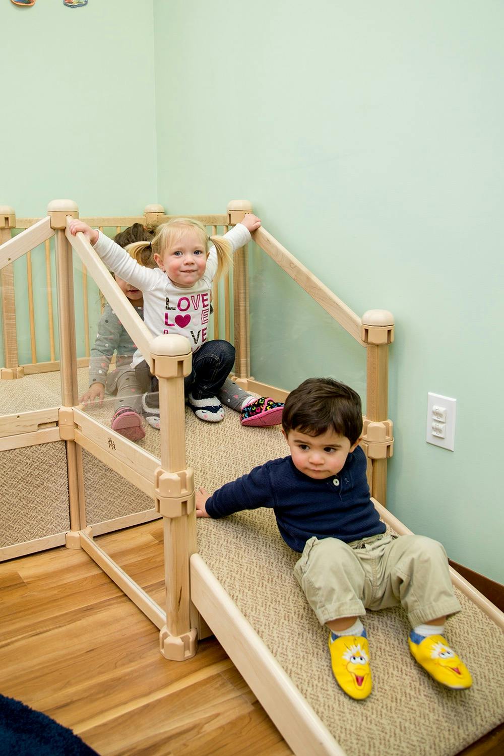 Children playing on a carpeted wooden structure