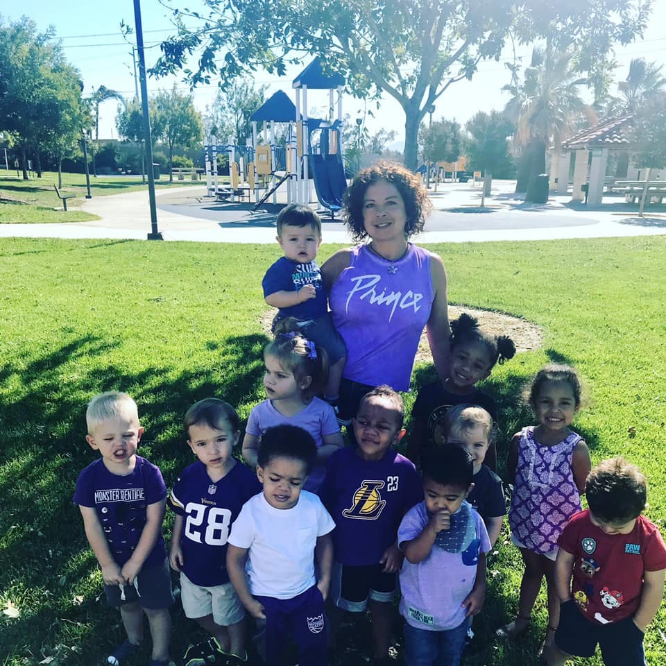 Adult and multiple children posing for a photo outdoors near a playground