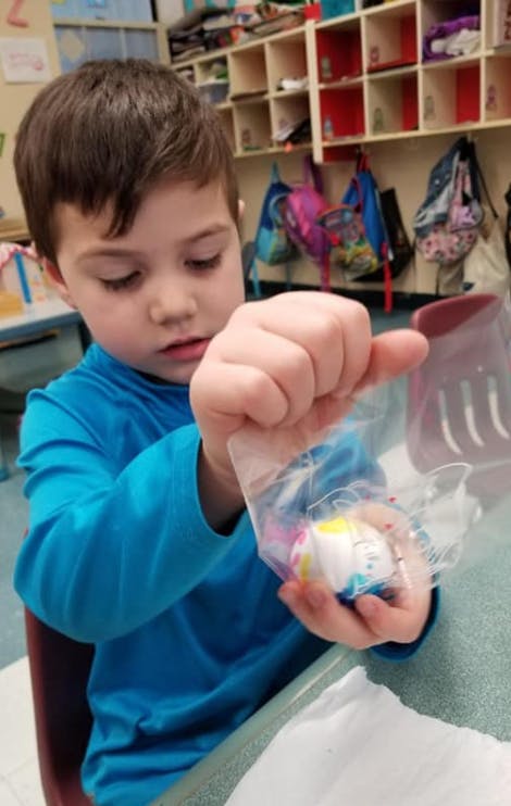 Child holding a small toy in a plastic bag
