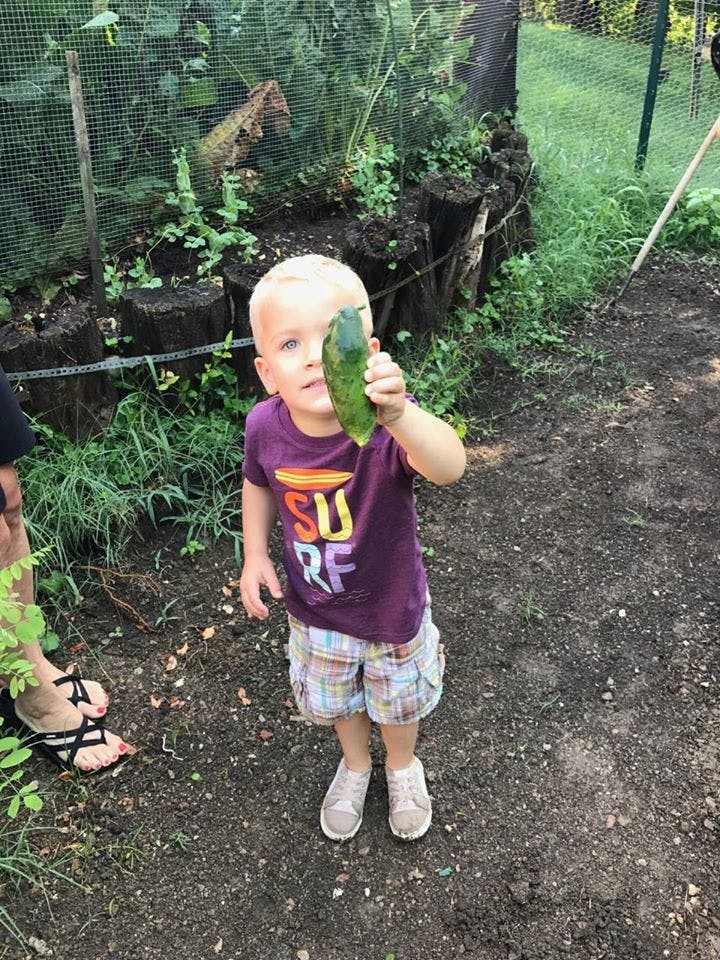 Child holding up a cucumber