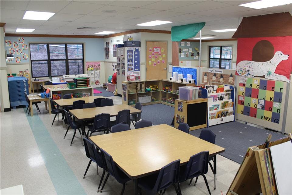 Classroom with tables, chairs, windows, and learning decorations