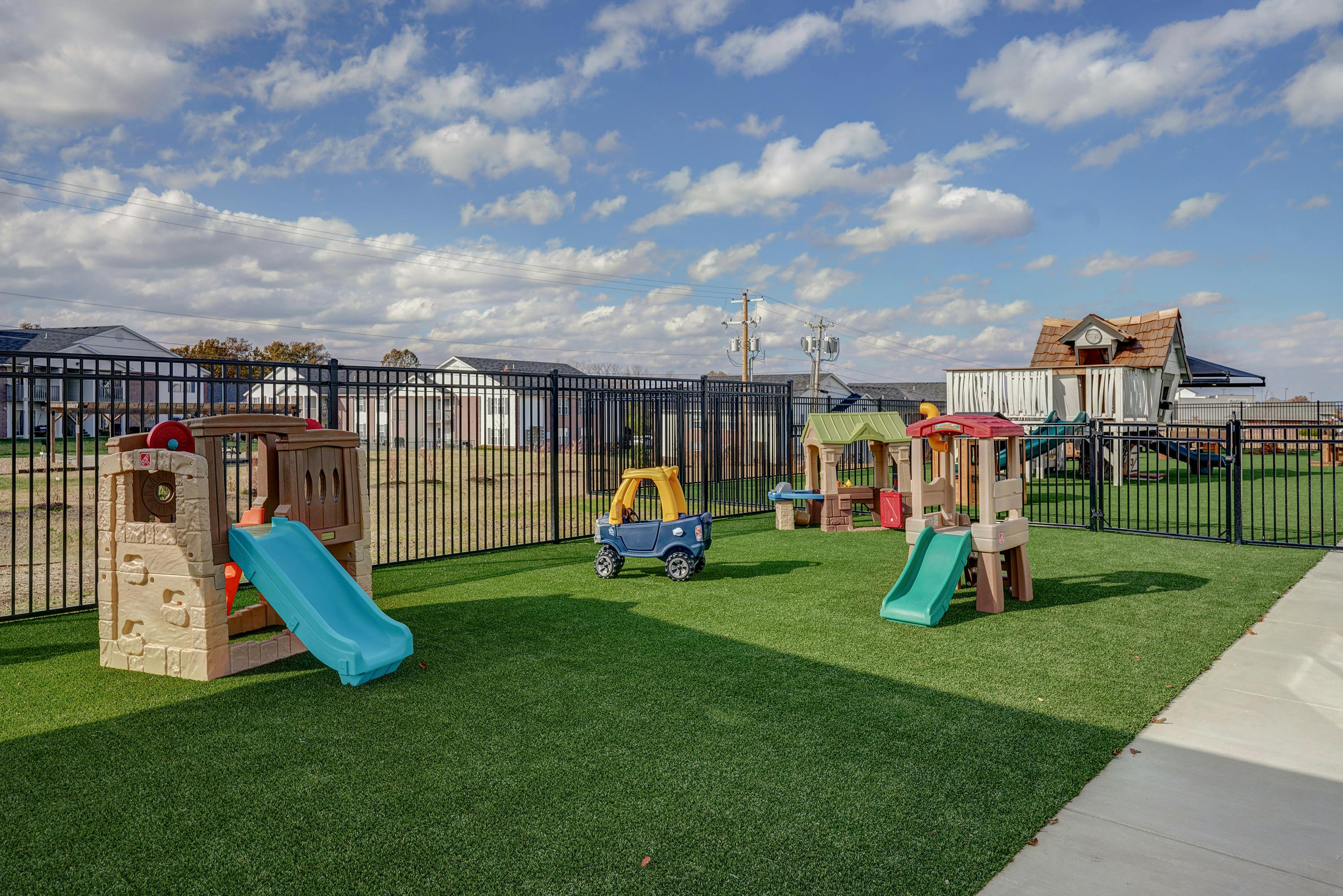 Playground with multiple play structures and slides on artificial turf