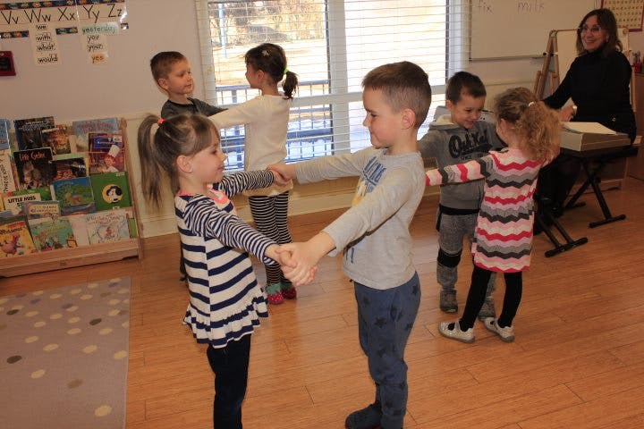 Children holding hands in a circle in a classroom