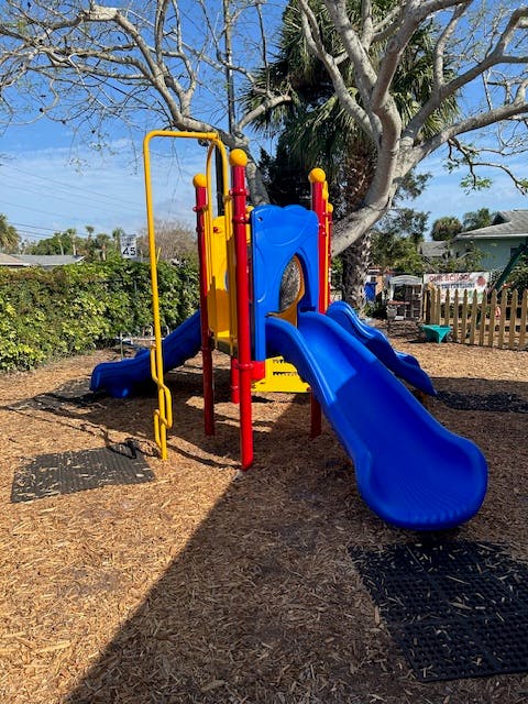 Playground structure with blue slides and yellow and red climbing elements
