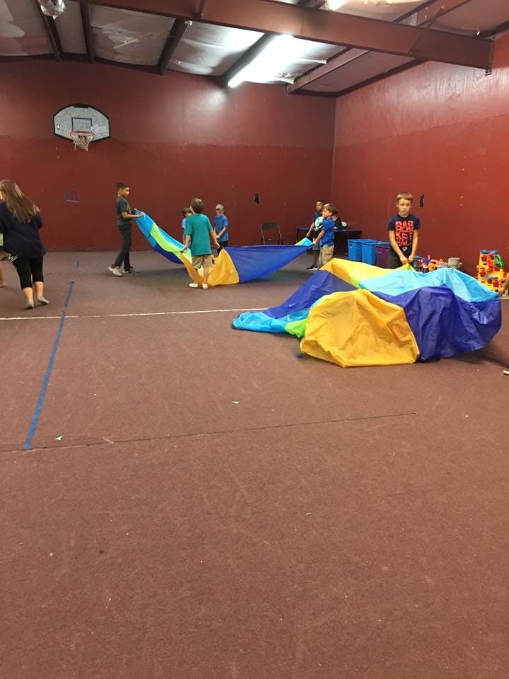 Children playing with a colorful parachute in a gym