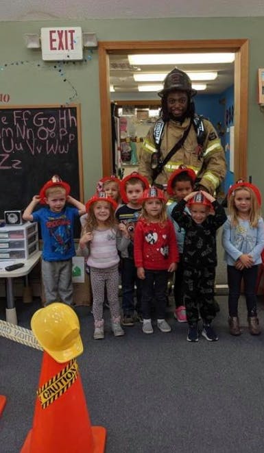 Firefighter with a group of children wearing fire hats