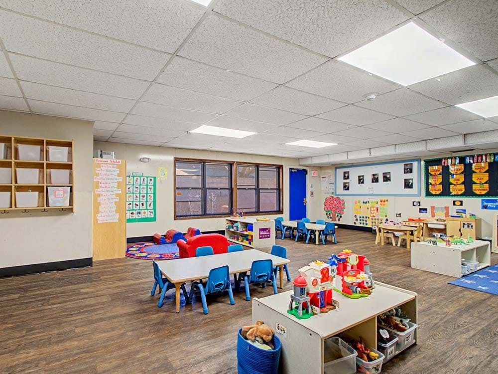 Empty colorful children's classroom with small tables and play areas