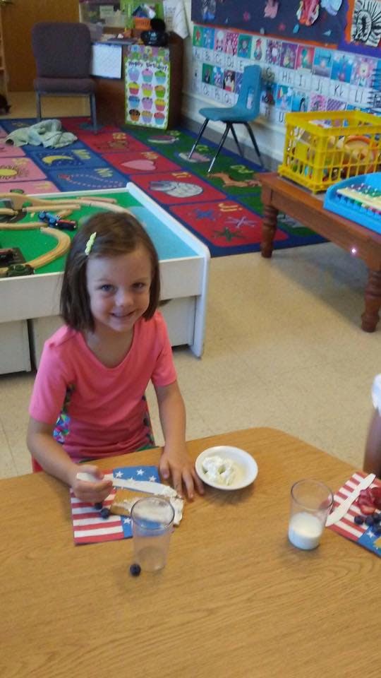 Child sitting at a table with a snack in a classroom