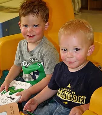 Two children sitting together, one holding a book