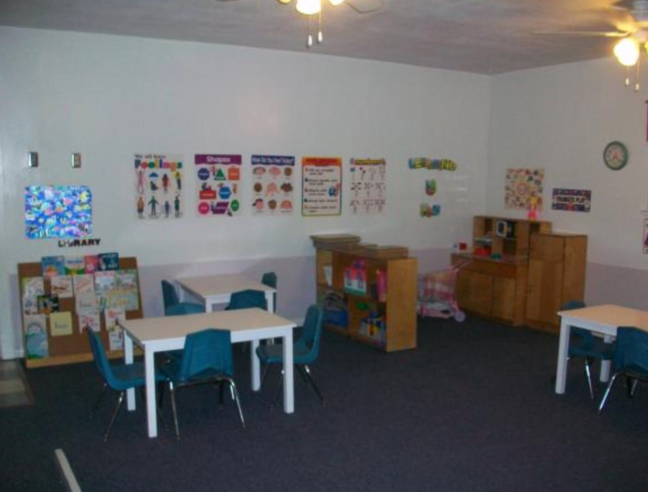 Classroom with small tables and chairs, bookshelves, and educational posters
