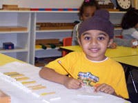 Child in a purple hat drawing at a table