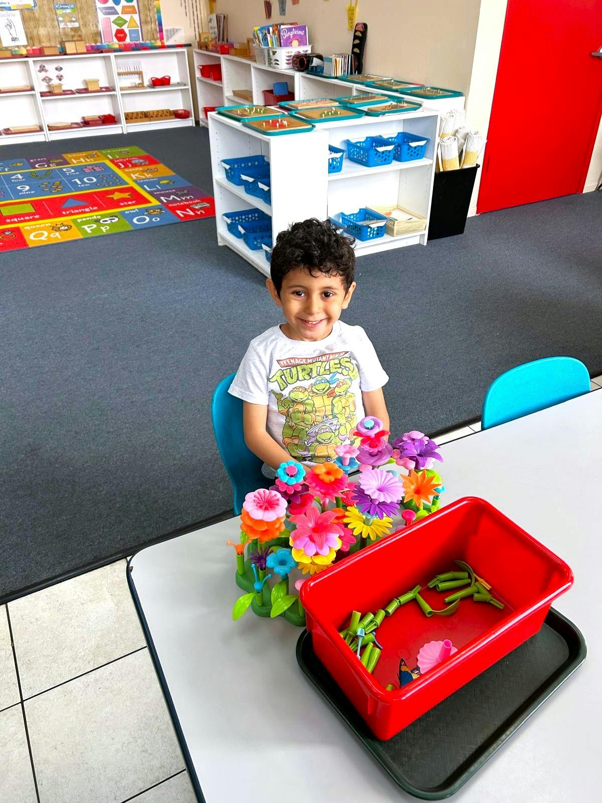 Child sitting at a table with colorful flower toys in a classroom