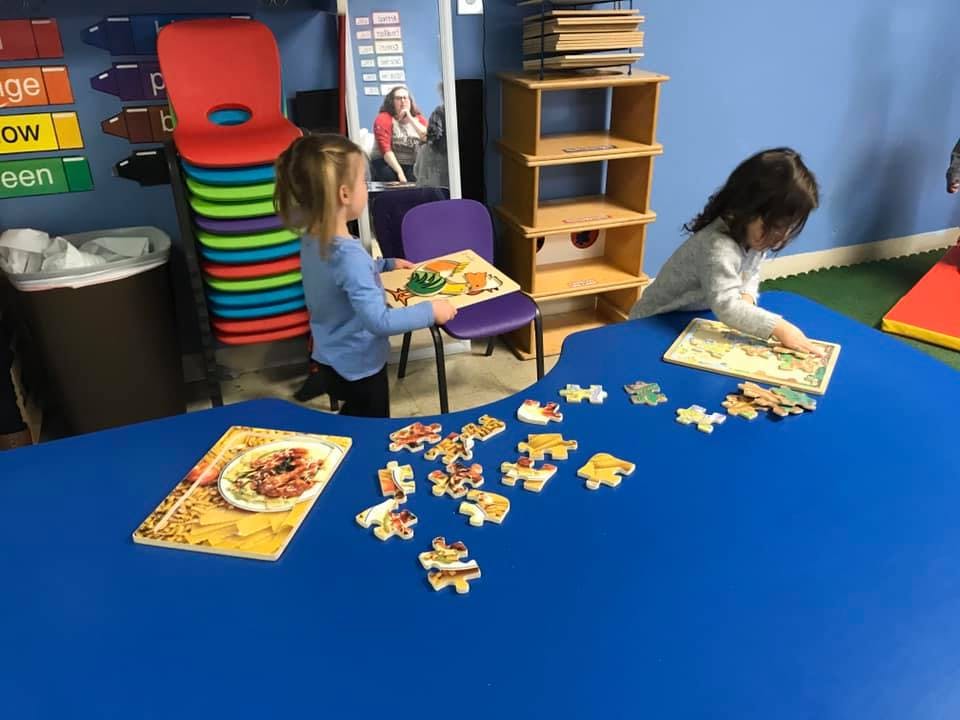 Two children playing with puzzles at a table