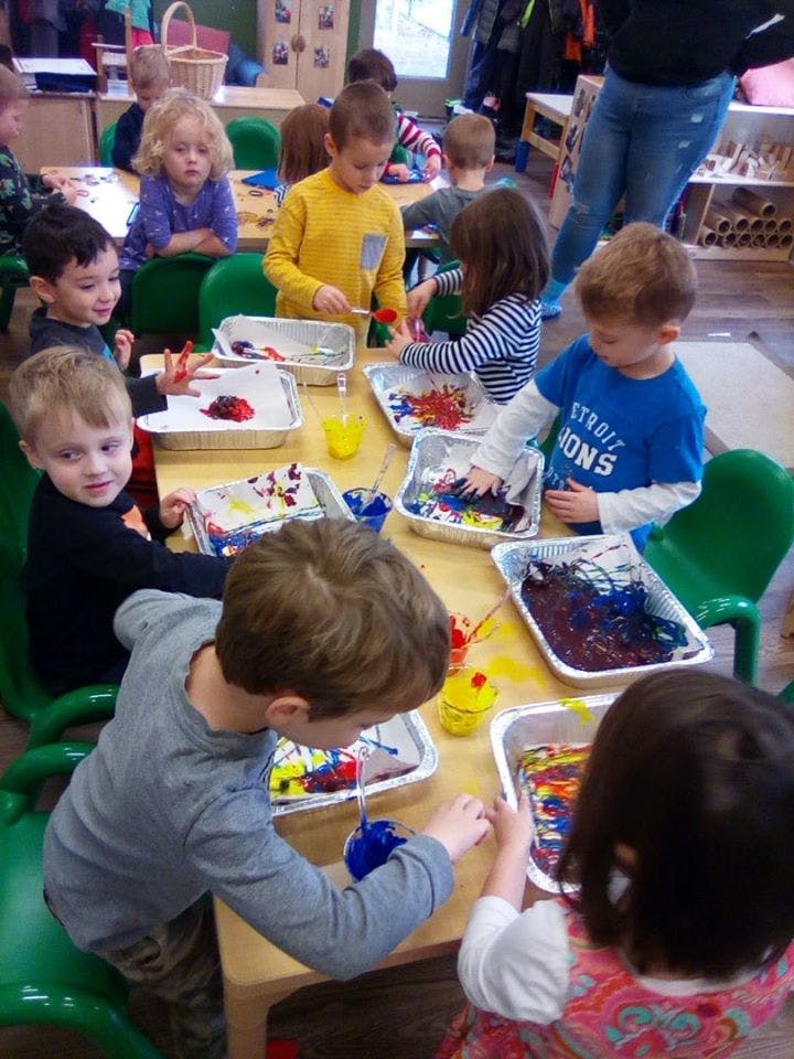Children painting at a table in a classroom