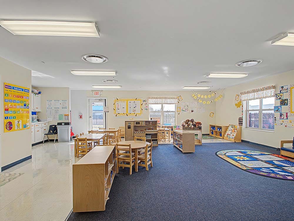Empty classroom with small tables, chairs, and learning materials