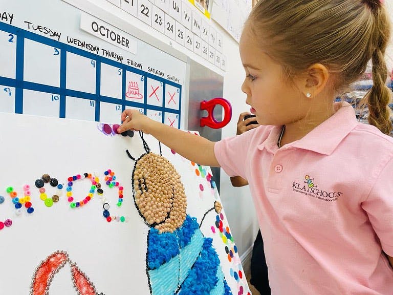 Child adding colorful beads to a craft project in a classroom