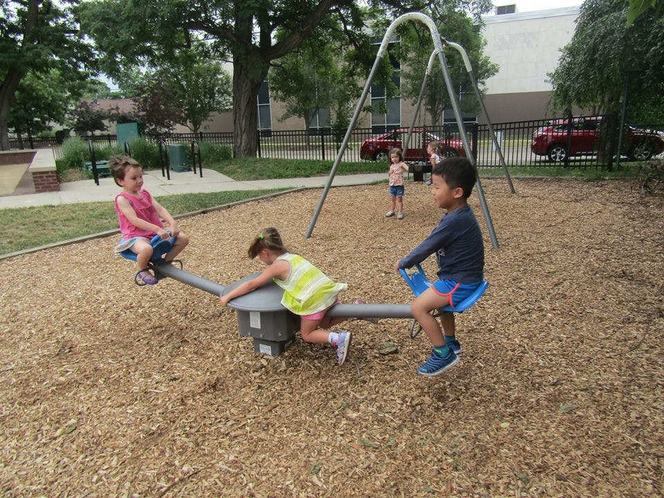Three children playing on a seesaw at a playground