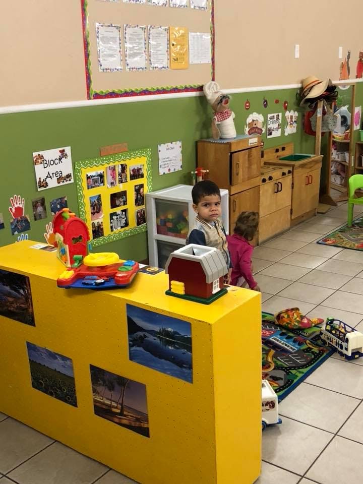 Child standing in a classroom with another child in the background