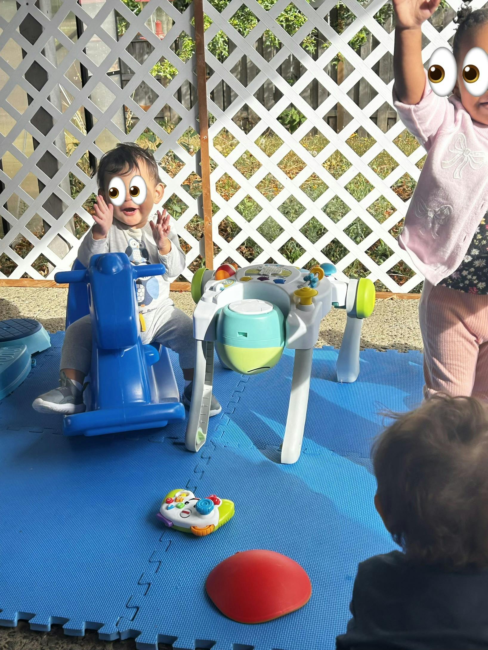 Three children playing with toys on a blue mat
