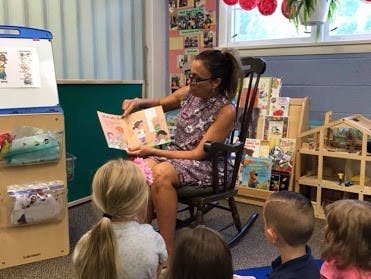 Adult reading a book to children in a classroom