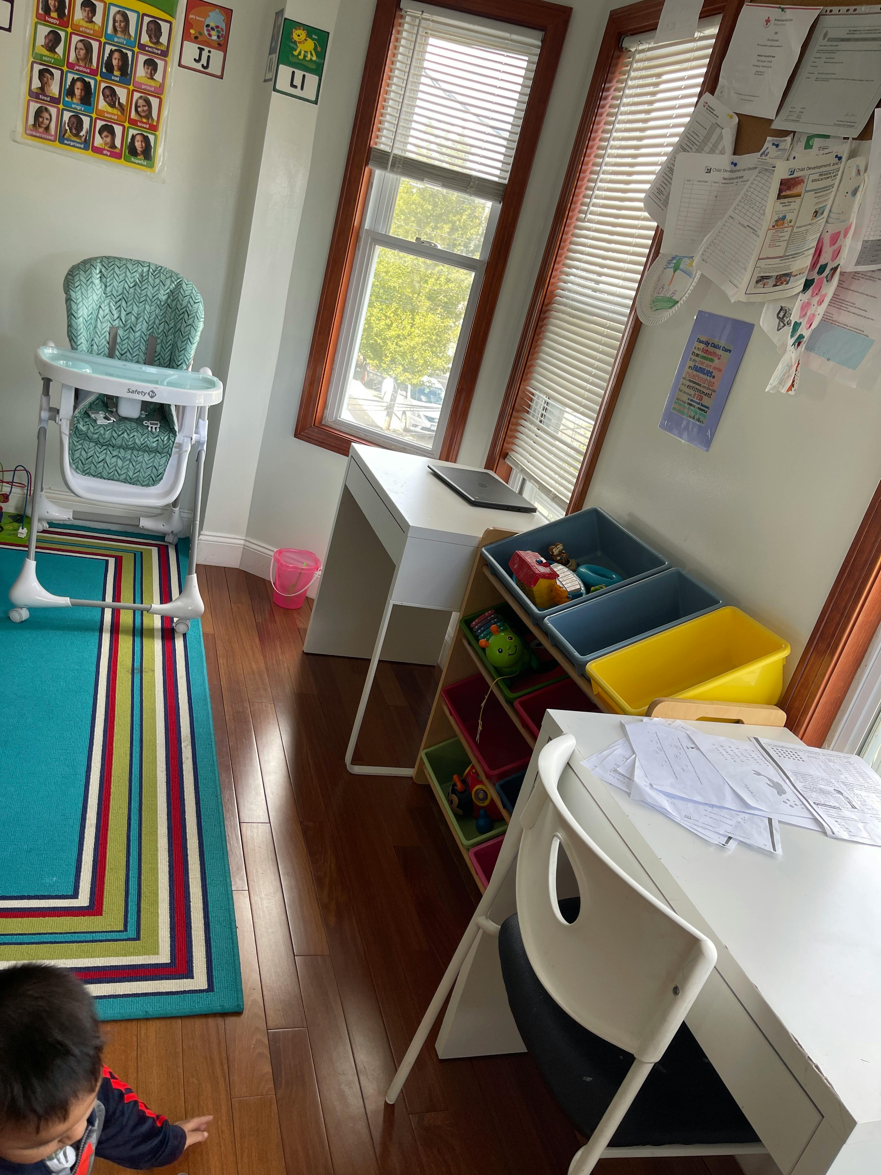 Child on floor in room with high chair, desk, and toy storage