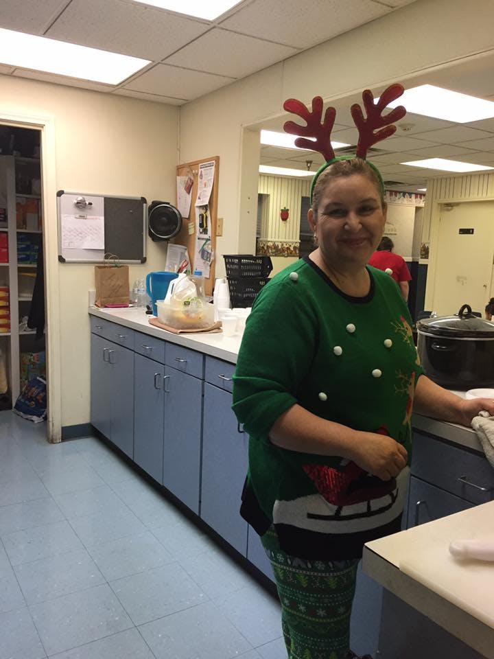 Person in reindeer antlers and a green sweater in a kitchen