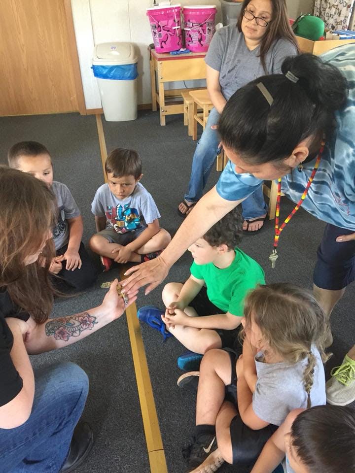Adults and children sitting on the floor in a circle, classroom