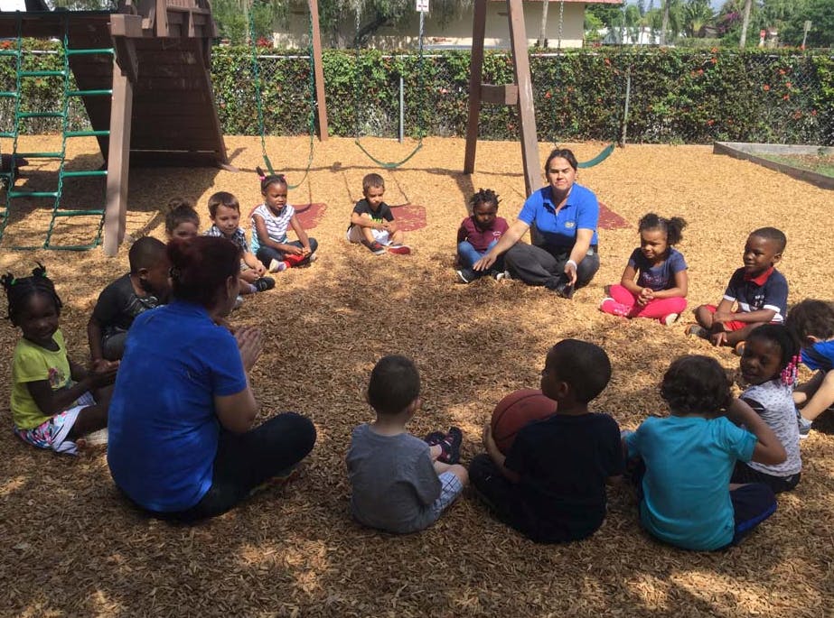 Adults and children sitting in a circle on a playground