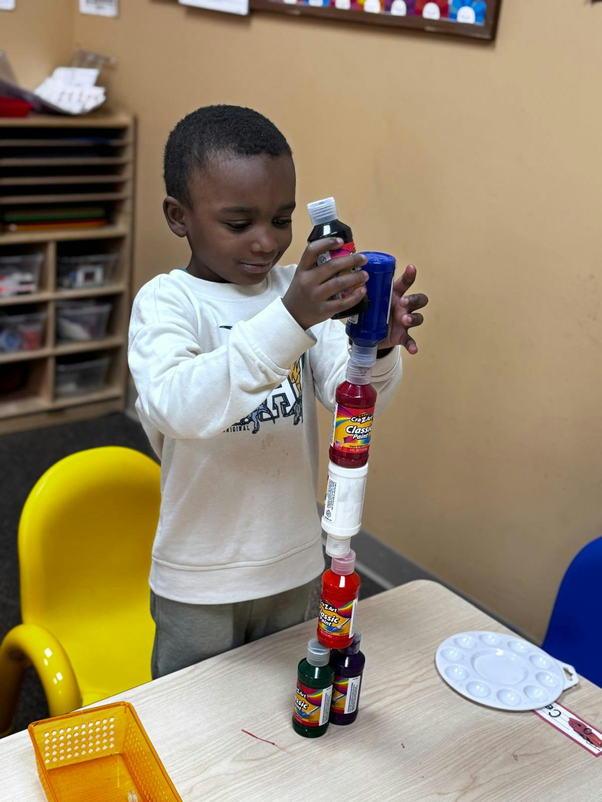 Child stacking bottles of paint in a classroom