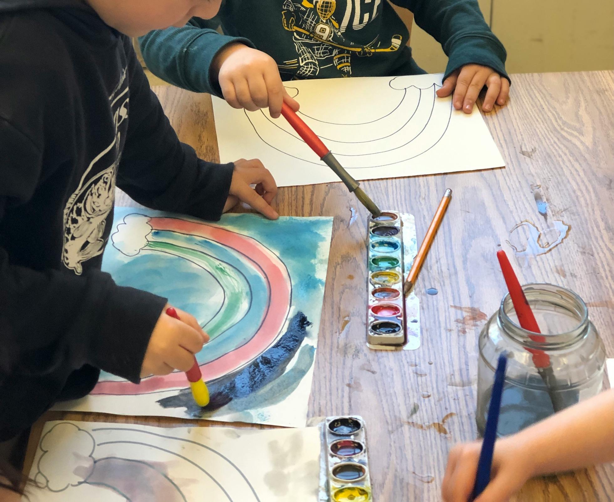 Children painting rainbow designs with watercolors