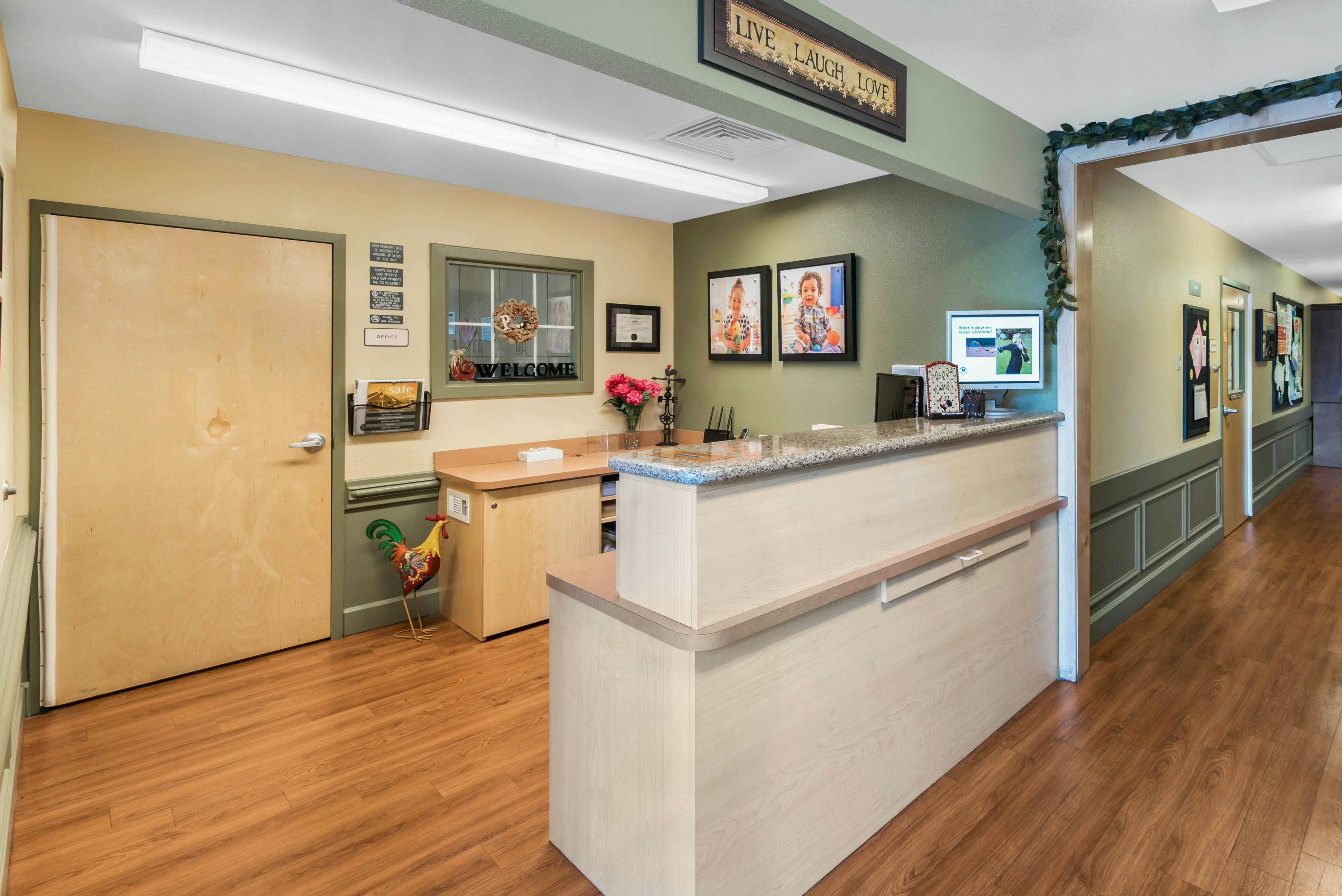 An office reception area with a light wood desk and two photos of children