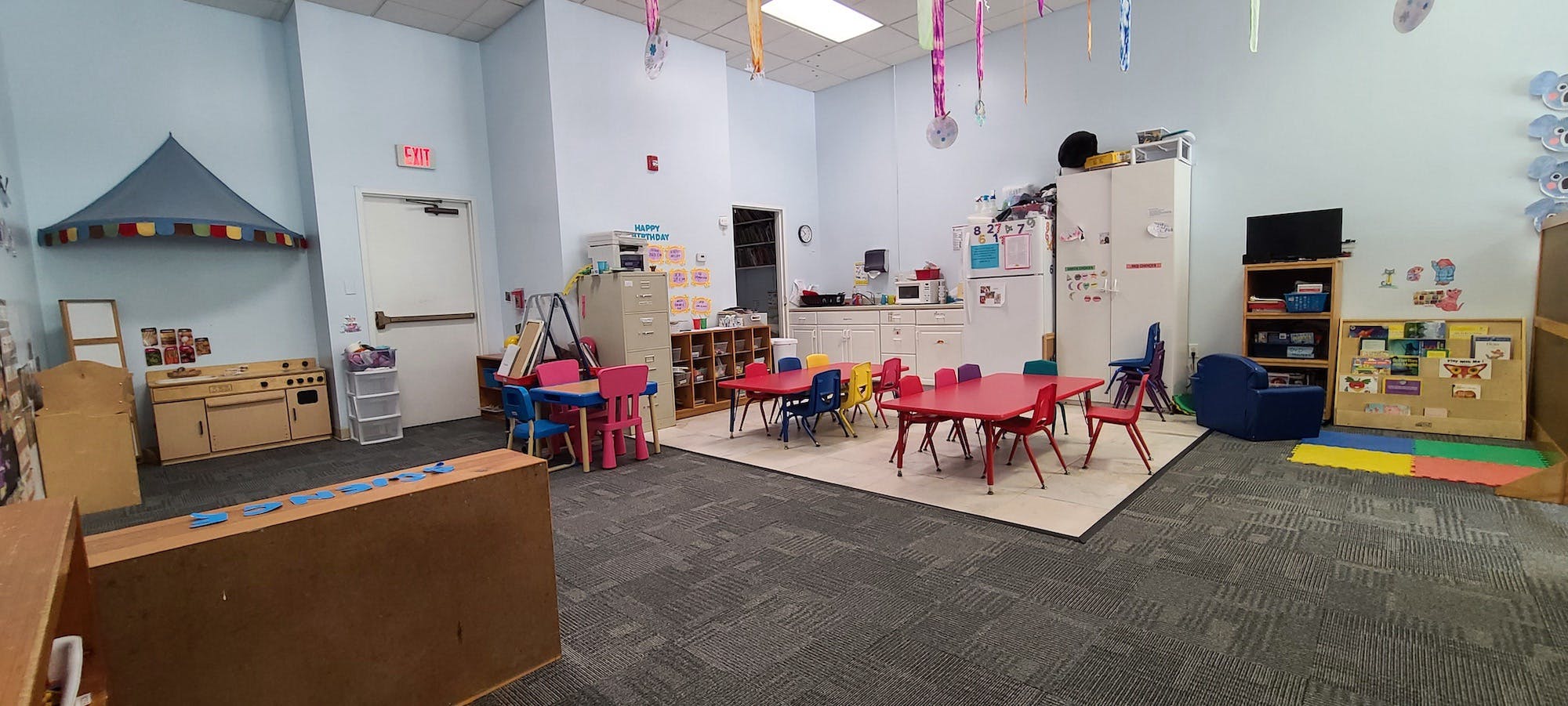 children's playroom with small tables and chairs, play kitchen, and books