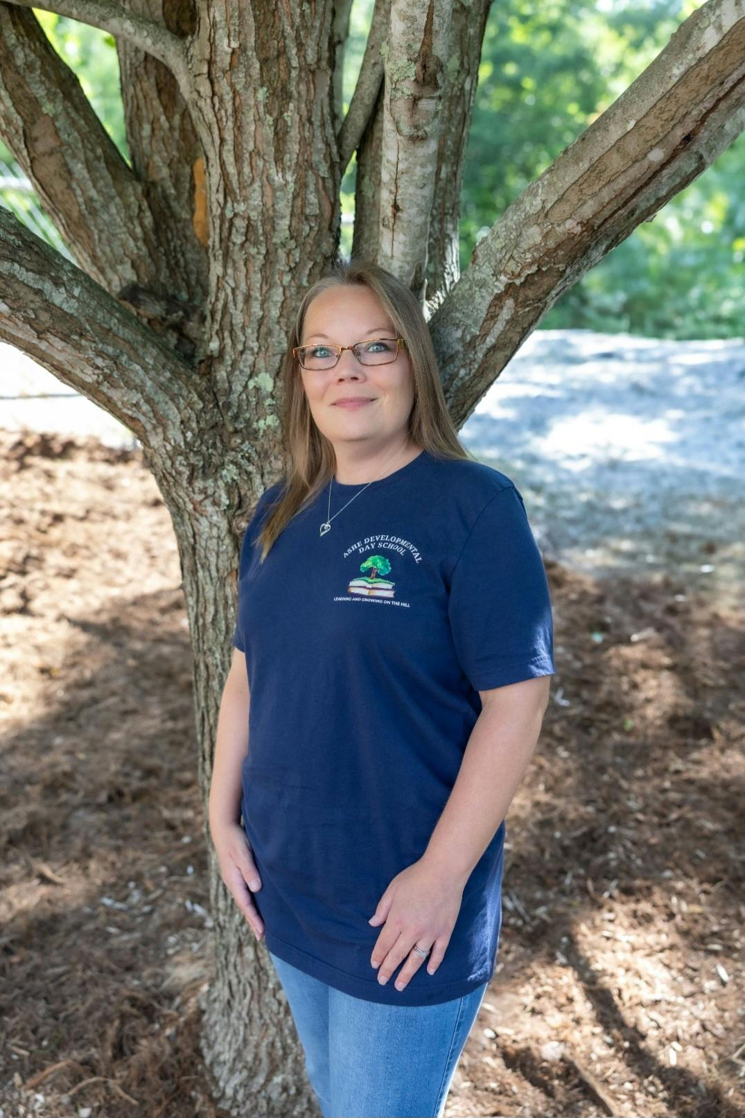 Person wearing an Ashe Developmental Day School t-shirt standing by a tree