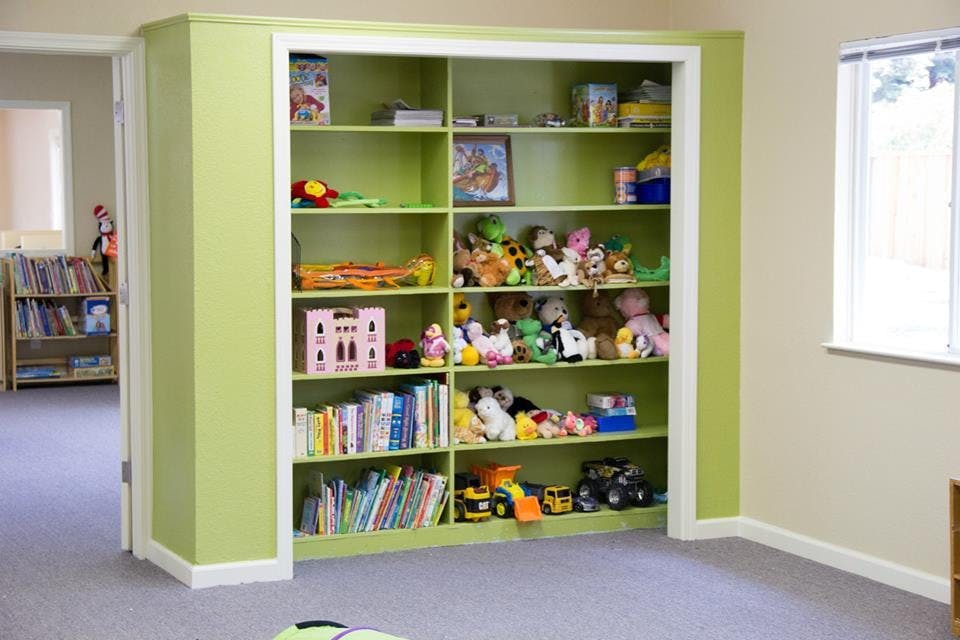 Green built-in shelves filled with books and toys
